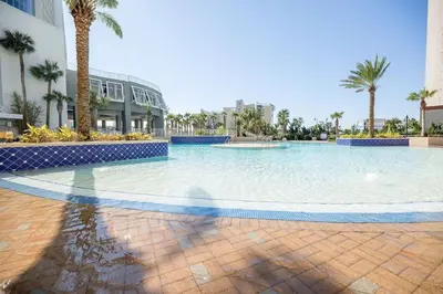 a large swimming pool with palm trees and a building at Laketown Wharf #1737 by Nautical Properties in Panama City Beach