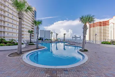 a swimming pool with palm trees and buildings at Spectacular 1BD Resort Condo! Amazing Gulf Views! Free Beach Chairs! by Dolce Vita Getaways PCB in Panama City Beach