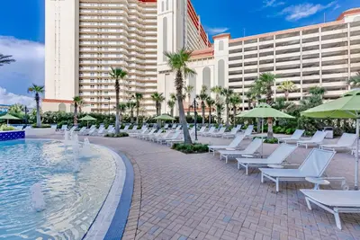 a pool with white lounge chairs and a hotel at Spectacular 1BD Resort Condo! Amazing Gulf Views! Free Beach Chairs! by Dolce Vita Getaways PCB in Panama City Beach
