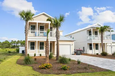 a white house with palm trees in front of it at Beach House - Sugary Sands by Panhandle Getaways in Panama City Beach