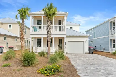 a house with a palm tree and a garage at Beach House - Sugary Sands by Panhandle Getaways in Panama City Beach