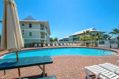 a pool with an umbrella and chairs and a table and chairs at Beachside Villas 933 in Santa Rosa Beach