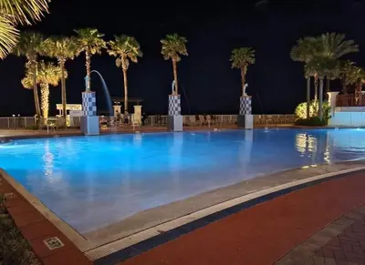 a large swimming pool with palm trees at night at Shores of Panama 808- 1 BedroomBunk Room, Free Fun! Updated! Sleeps 6, condo in Panama City Beach