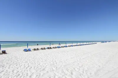 a beach with a line of chairs and the ocean at Shores of Panama 707 - 2 BedroomBunks Sleeps 8, Reserved Parking Free Fun! condo in Panama City Beach