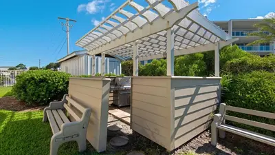 a white pergola over a table and two benches at Beachcrest 405 in Santa Rosa Beach