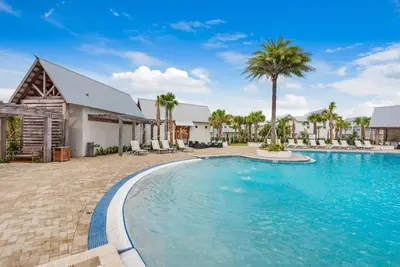 a swimming pool in front of a house with palm trees at Town of Prominence 80C- The Wright Place in Santa Rosa Beach