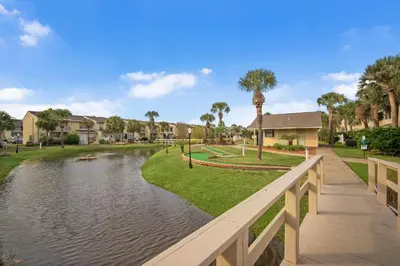a bridge over a pond in a park with houses at Gulf Highlands #106 in Panama City Beach