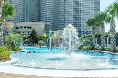 a fountain in a swimming pool with palm trees at Emerald Beach 431 in Panama City Beach