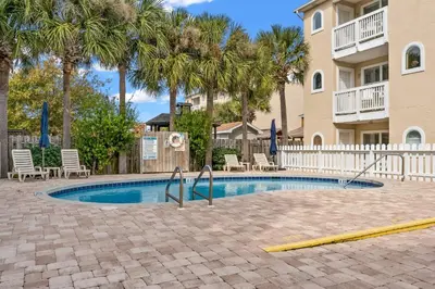 a swimming pool with chairs and palm trees at Merrimac Resort #12 in Panama City Beach