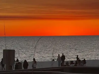a group of people standing on the beach at sunset at The Coastal Cabana in Panama City Beach