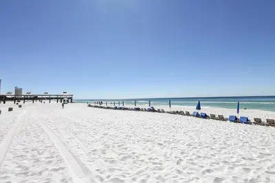 a beach with chairs and a pier and the ocean at Shores of Panama # 1902 condo in Panama City Beach