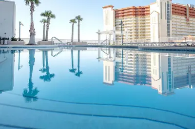 a pool of blue water with palm trees and buildings at Laketown Wharf #1106 by Nautical Properties in Panama City Beach
