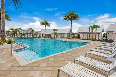 a swimming pool with lounge chairs and palm trees at Town of Prominence 67C - Pour Beach Life in Inlet Beach