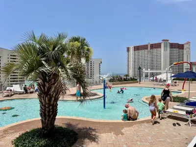 a family playing in a swimming pool at a resort at Low Floor 3BD plus Bunks Condo! Family Resort! 5 Pools! Free Beach Chair Service! in Panama City Beach