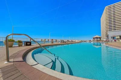 a swimming pool with an umbrella in the middle at Treasure Island #1207 in Panama City Beach