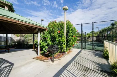 a patio with a fence and a bush with flowers at Celadon 302 in Panama City Beach
