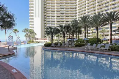 a large swimming pool with palm trees and a large building at Shores of Panama 1427 condo in Panama City Beach