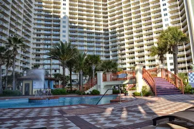 a resort with a pool and palm trees and buildings at Shores of Panama 723 condo in Panama City Beach