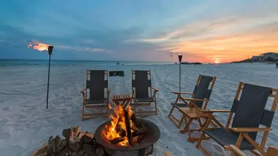 a fire pit on a beach with chairs and the ocean at Hidden Beach 216 in Santa Rosa Beach