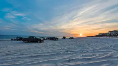 a group of cars parked on the beach at sunset at Hidden Beach 216 in Santa Rosa Beach
