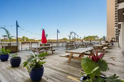 a deck with wooden picnic tables and potted plants at Laketown Wharf #1115 in Panama City Beach