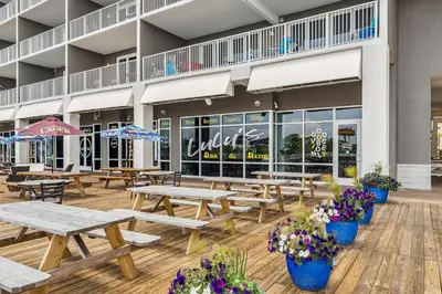 a patio with picnic tables and flowers in front of a building at Laketown Wharf #1206 in Panama City Beach