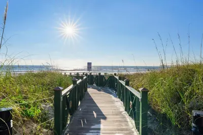 a boardwalk to the beach with the sun in the sky at Grand Panama #1-2101 in Panama City Beach