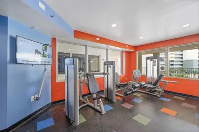 a gym with two tread machines in a room with orange walls at Shores Of Panama #1508 in Panama City Beach