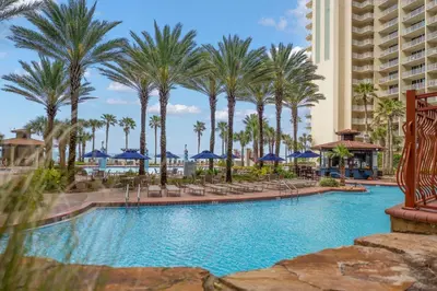 a pool at a resort with palm trees and blue umbrellas at Shores Of Panama #0220 in Panama City Beach