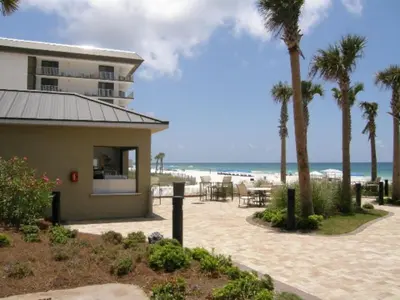 a building next to a beach with palm trees at Grand Panama Beach Resort - The Grand #704 in Panama City Beach