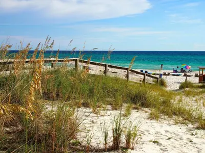 a beach with a wooden fence and the ocean at Ocean Reef 703 in Panama City Beach