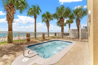 a swimming pool with palm trees and a fence at Tropic Winds 801 in Panama City Beach