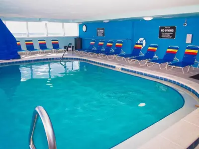a swimming pool in a hotel room with blue walls and chairs at Tropic Winds 1604 in Panama City Beach