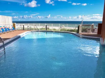 a large swimming pool with the ocean in the background at Tropic Winds 1406 in Panama City Beach