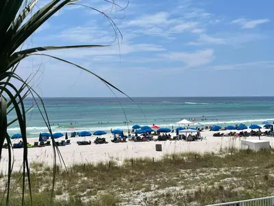 a beach with blue umbrellas and chairs and the ocean at Ocean Reef 1308 in Panama City Beach