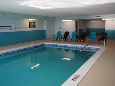 a swimming pool with chairs and a table in a room at Ocean Reef 1604 in Panama City Beach
