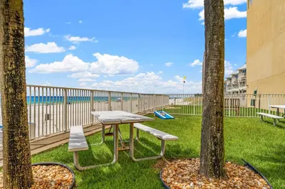 a picnic table and two trees with a playground at Tropic Winds 1909 in Panama City Beach