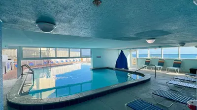 a large swimming pool in a building with chairs at Tropic Winds 1706 in Panama City Beach