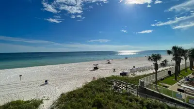 a view of a beach with palm trees and the ocean at Tropic Winds 1706 in Panama City Beach