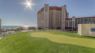 a golf course on the beach with buildings and the ocean at Laketown Wharf #1517 by Nautical Properties in Panama City Beach