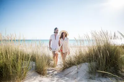 a man and woman walking through the sand at the beach at Southern Charm in Santa Rosa Beach