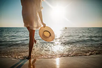 a woman walking on the beach with a straw hat at Daydreams By The Sea in Seacrest