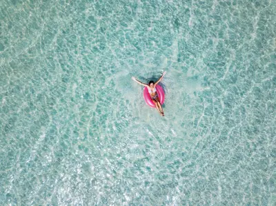 a woman in a pink swimsuit swimming in the water at The Golden Pearl in Watersound Beach