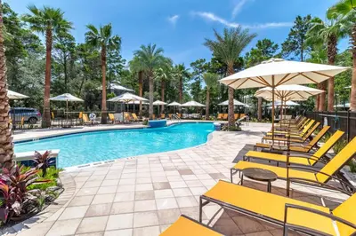 a swimming pool with yellow chairs and umbrellas at 30A Magnolia Cottages by the Sea by Panhandle Getaways in Seacrest