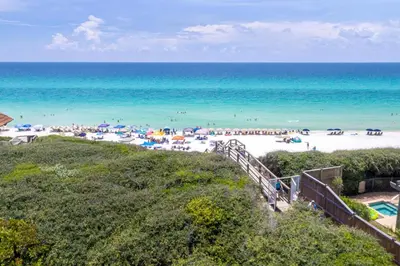 a beach with umbrellas and people on the beach at 30A Magnolia Cottages by the Sea by Panhandle Getaways in Seacrest