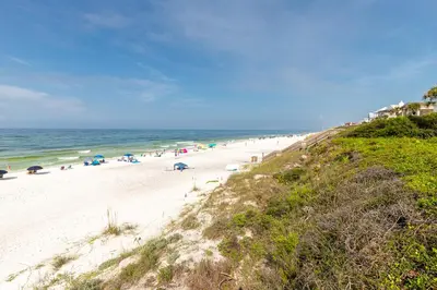 a beach with people and umbrellas and the ocean at Palms of Seagrove D5, Steps to the Beach, Sleeps 4, Pool, 2 bikes and 5 mins from Seaside in Seagrove Beach