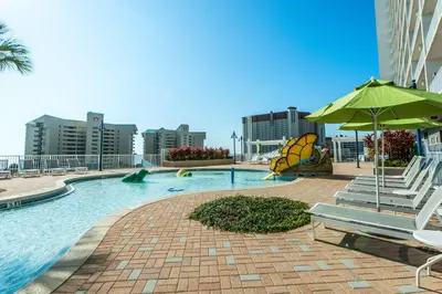a swimming pool with chairs and an umbrella at Laketown Wharf 801 by Emerald Coast Retreats in Panama City Beach