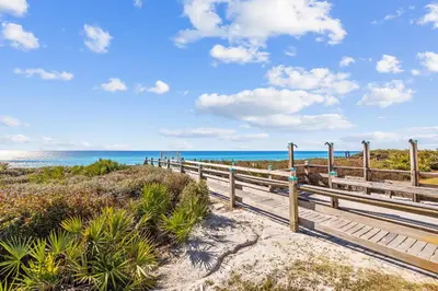 a boardwalk to the beach with the ocean in the background at Aqua Waters by 30A Escapes in Rosemary Beach