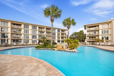 a swimming pool in front of a building with palm trees at HP 16E Beach Treat by 30A Escapes in Rosemary Beach