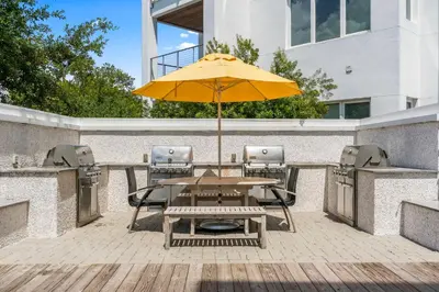 a wooden table with an umbrella on a patio at The Pointe Unit 121 by 30A Escapes in Rosemary Beach